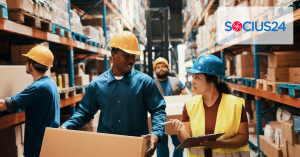 Group of warehouse workers in hard hats and safety gear, carrying boxes and clipboards